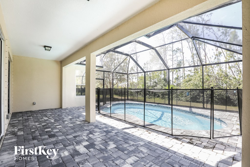 the pool is in the back of the house with a large window and a fence