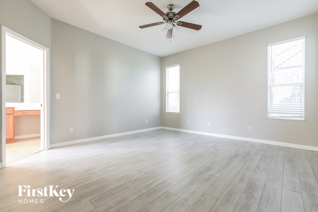 an empty living room with a ceiling fan and wood floors