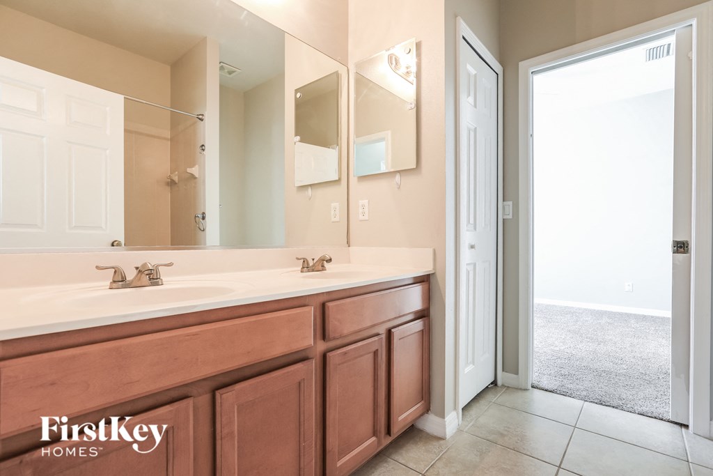 a bathroom with a sink and a mirror and a door to the shower