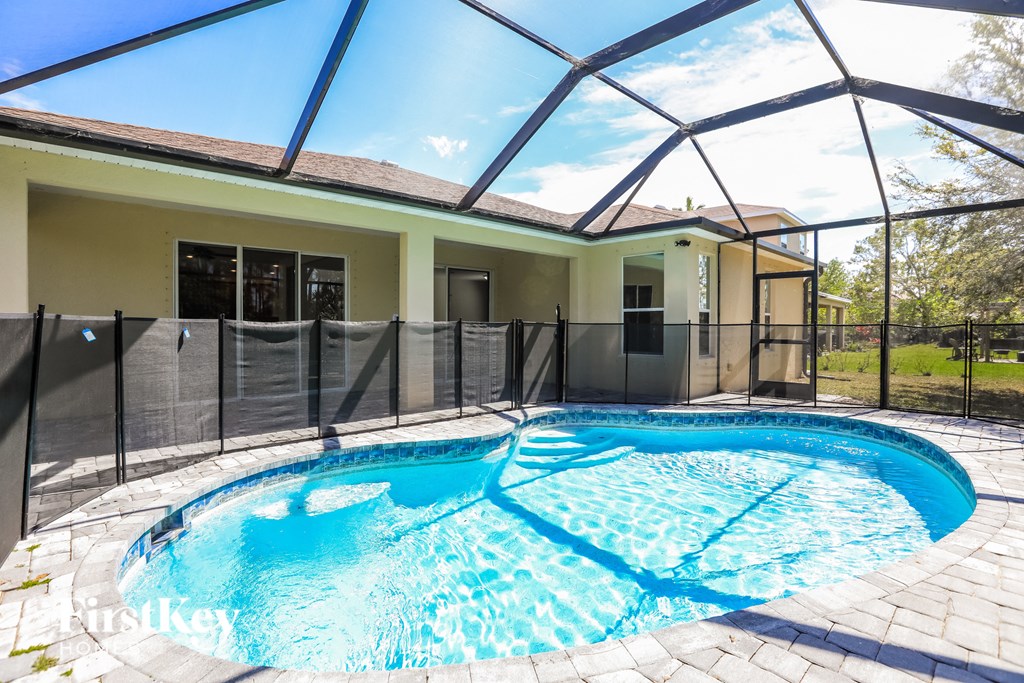a resort style swimming pool in front of a house with a screened in pool