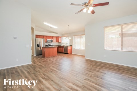 A spacious living room with wooden floors and a ceiling fan.
