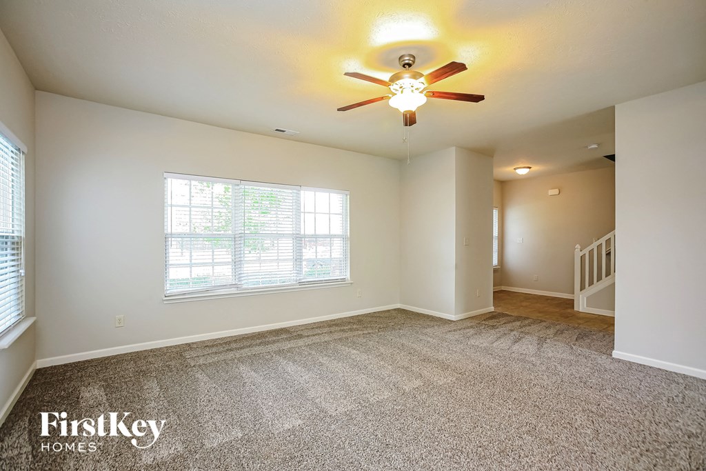 a living room with carpet and a ceiling fan