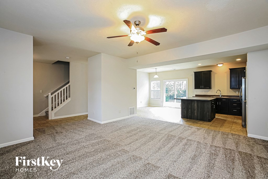 an empty living room and kitchen with a ceiling fan