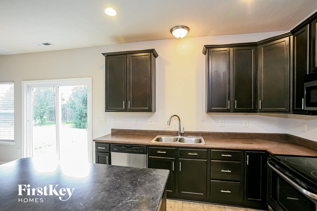 a kitchen with black cabinets and a sink and a window