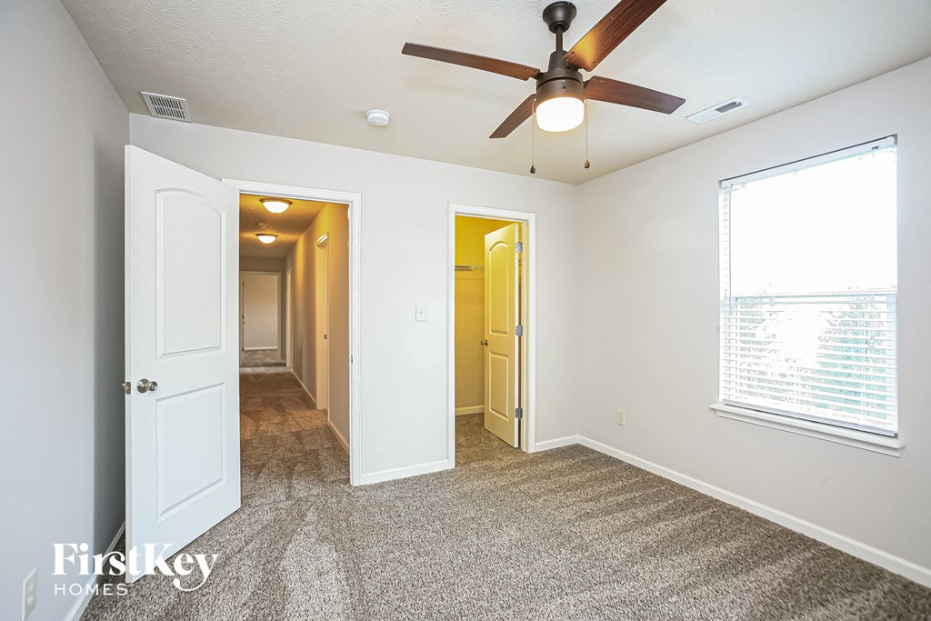 a living room with a ceiling fan and a door to a hallway