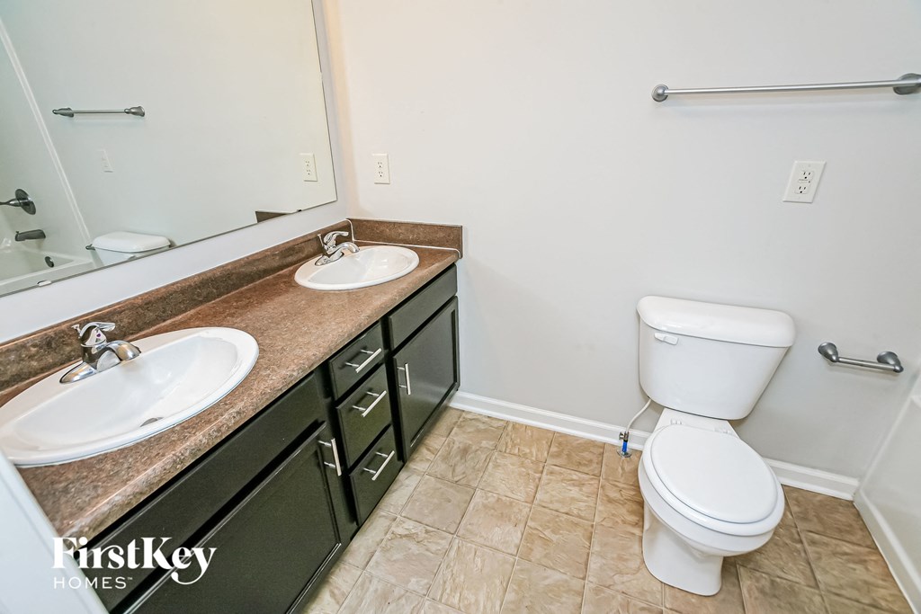 a bathroom with two sinks and a toilet and a mirror