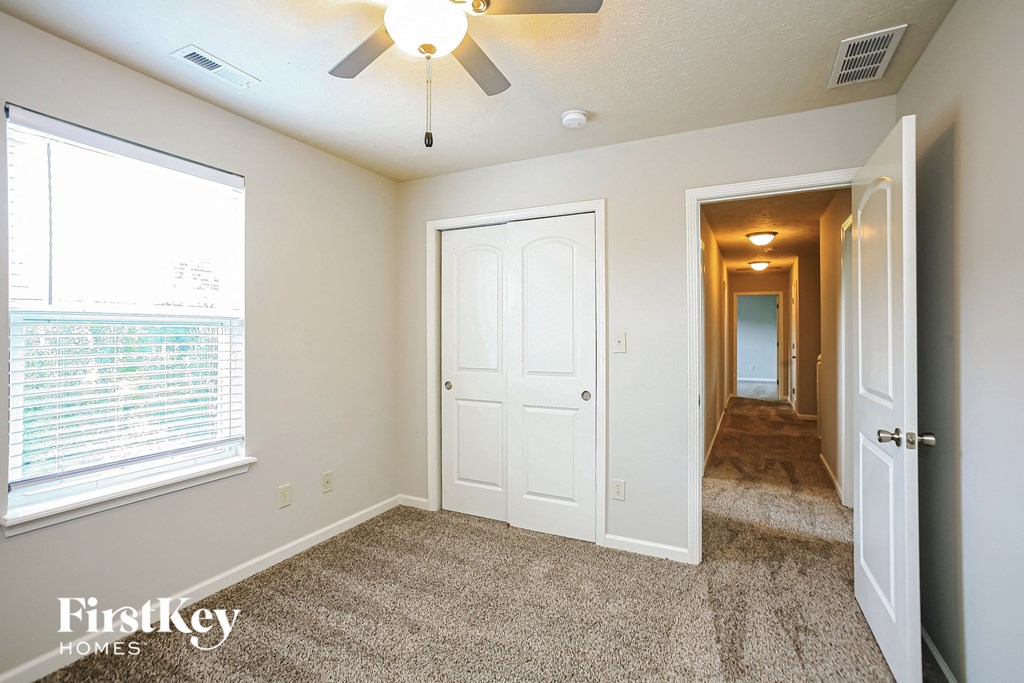 a bedroom with a ceiling fan and a door to a hallway