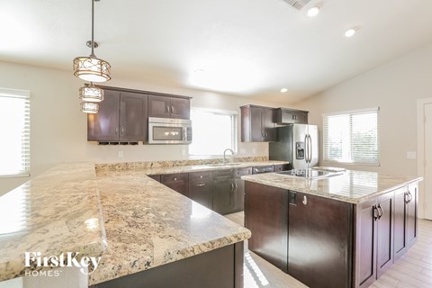 a kitchen with granite counter tops and dark wood cabinets