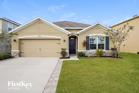 a beige house with a driveway and a lawn