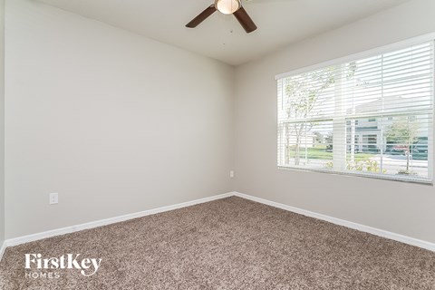 the master bedroom has carpeted floors and a large window