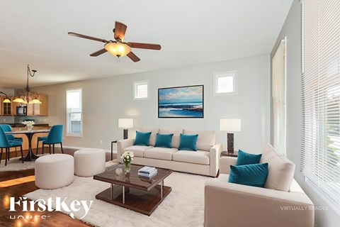 A living room with a white couch and a painting on the wall.