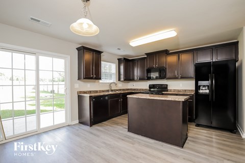 A kitchen with dark brown cabinets and a black refrigerator.