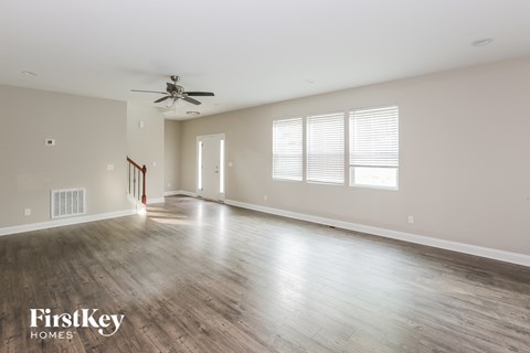 A spacious room with wooden flooring and a ceiling fan.