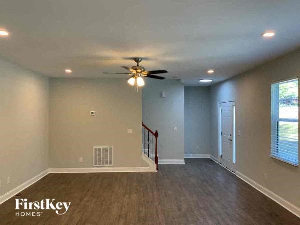 A spacious room with a ceiling fan and wooden flooring.