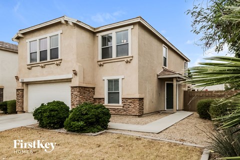 a beige house with a garage and a sidewalk in front