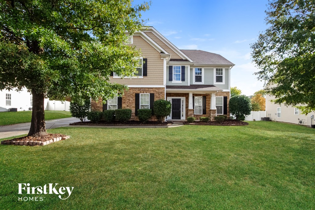 a large lawn in front of a house with a tree