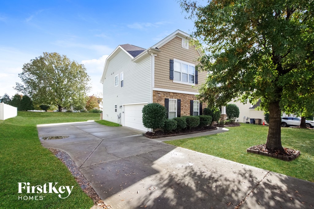 a house with a driveway and a tree in front of it