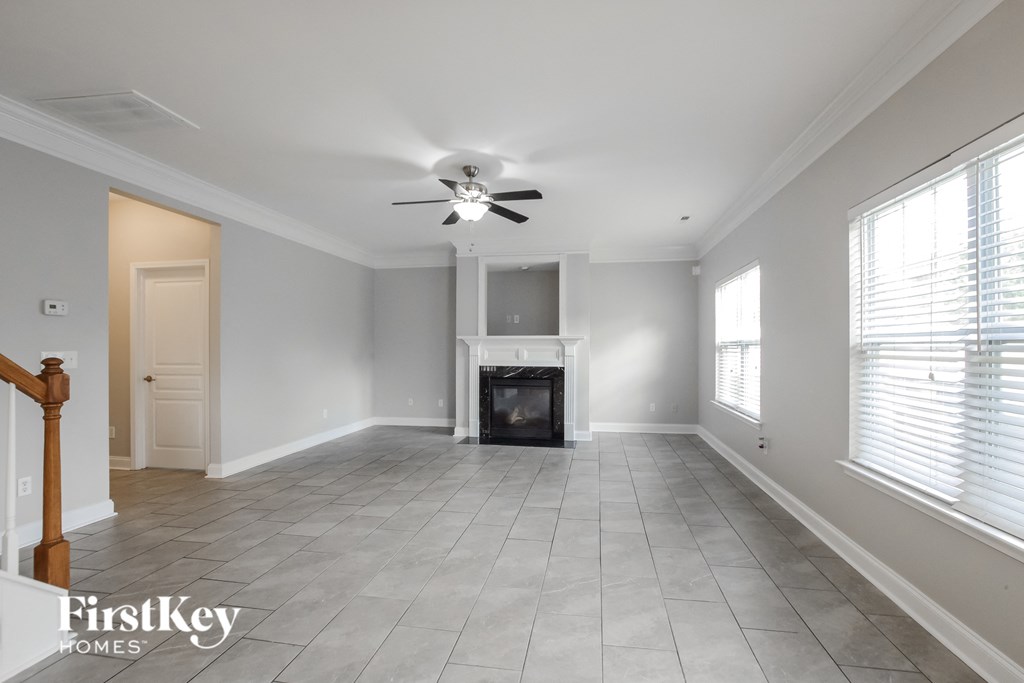 an empty living room with a fireplace and a ceiling fan