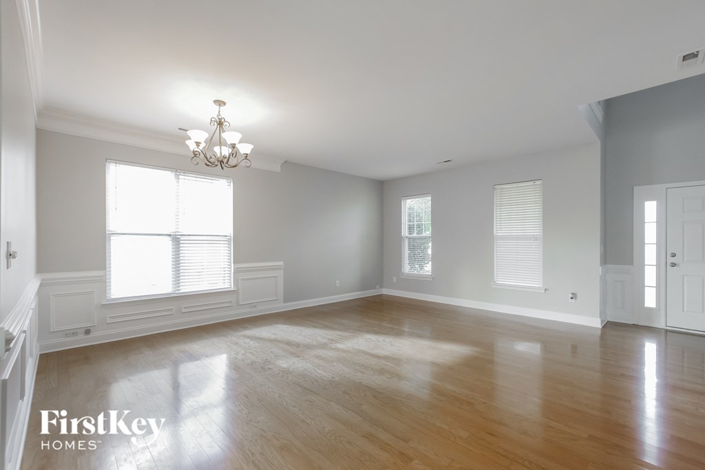 an empty living room with wood floors and a chandelier