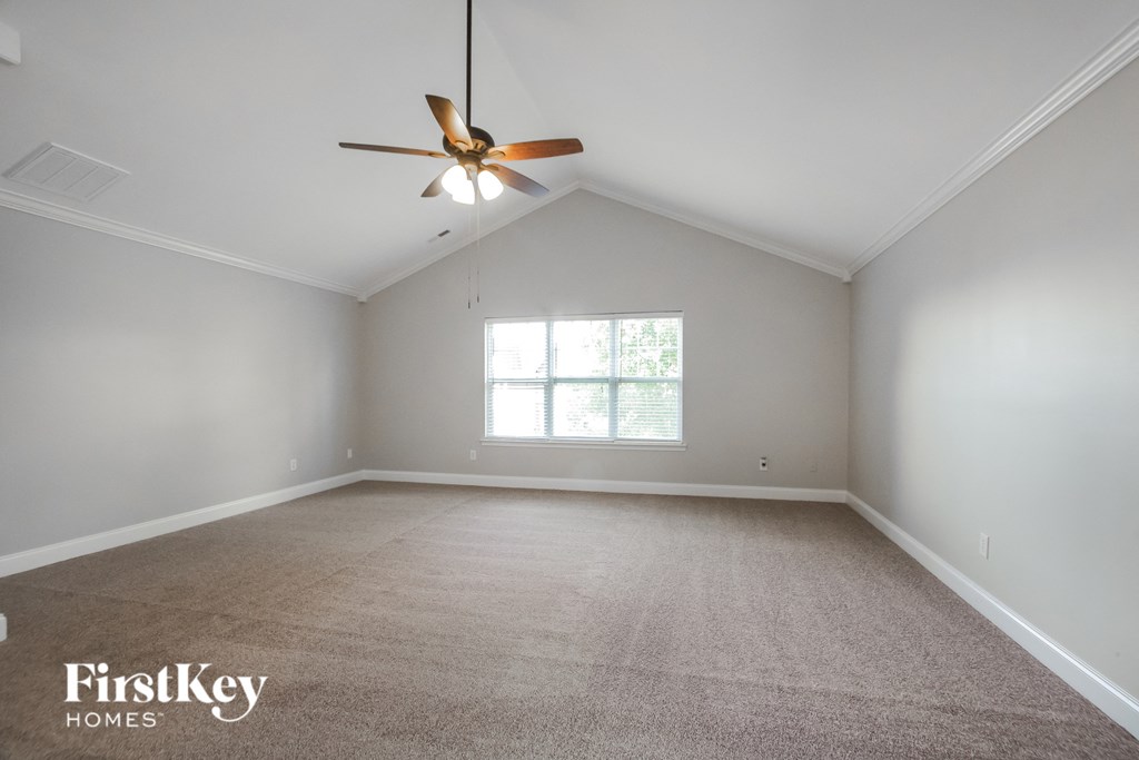 an empty living room with a ceiling fan and a window
