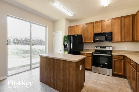 A kitchen with wooden cabinets and a black refrigerator.