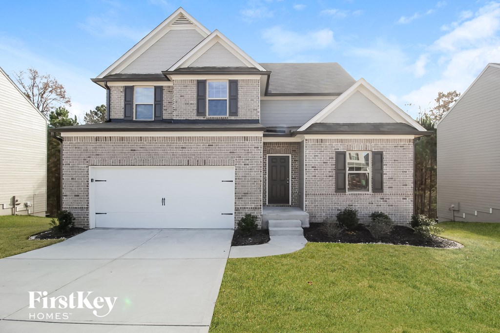 a brick house with a white garage door and a lawn