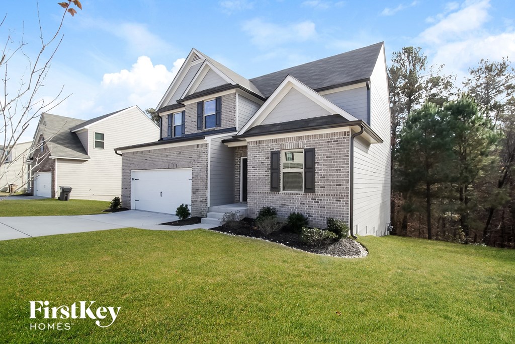 a white brick house with a lawn and a white garage door
