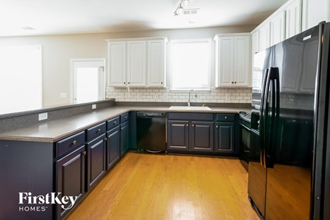 a black and white kitchen with wood floors and white cabinets