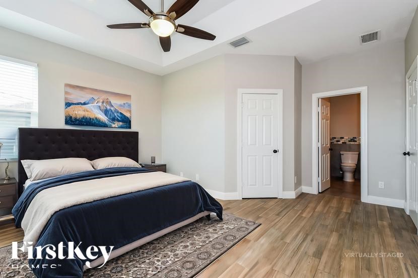 A bedroom with a large bed and a ceiling fan.