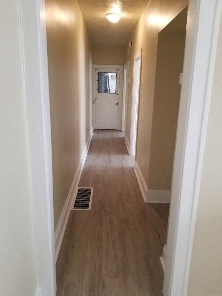 a hallway with wooden floors and a white door