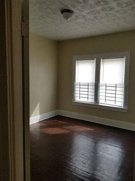 an empty room with a window and wooden floors