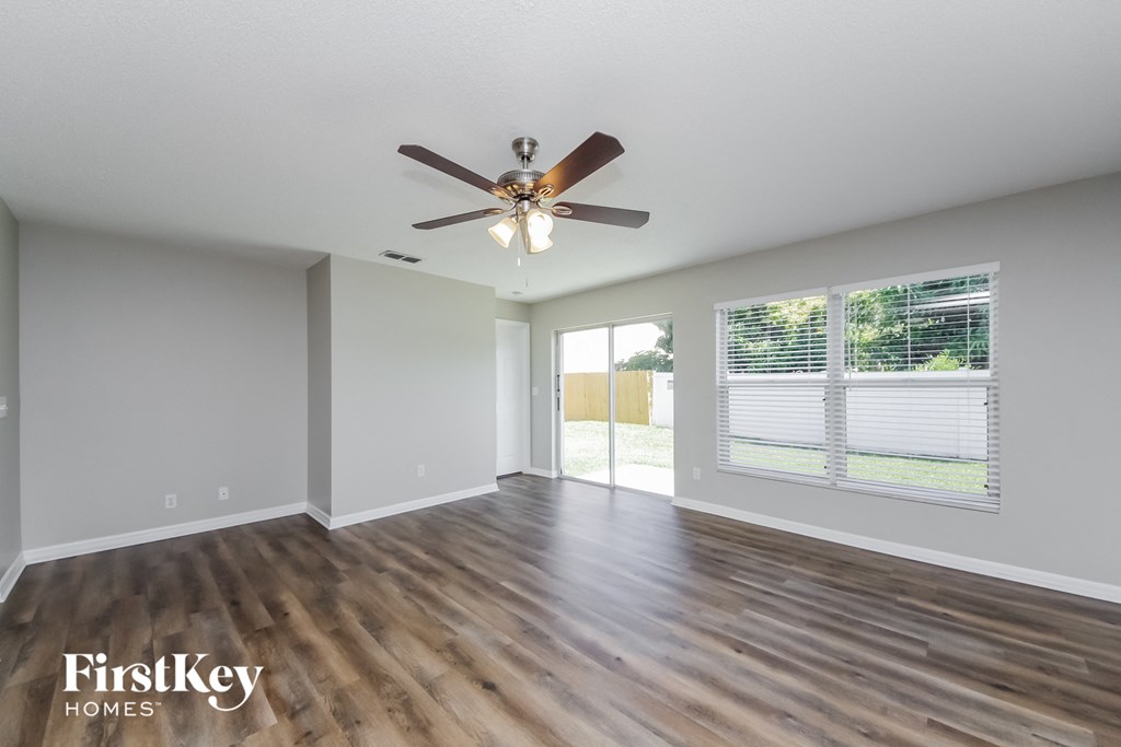 A spacious room with a ceiling fan and wooden flooring.
