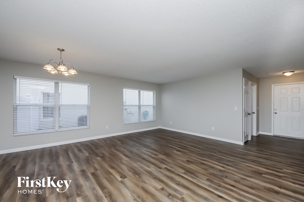 A room with wooden flooring and a chandelier.