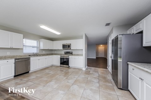 A kitchen with white cabinets and a tile floor.