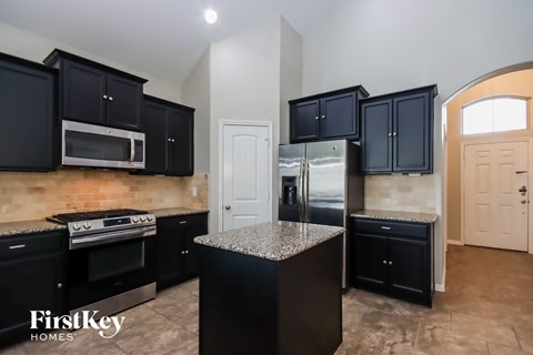 A kitchen with black cabinets and a granite countertop.