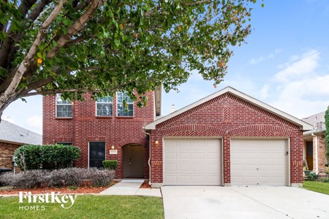 a brick house with a white garage door and a tree