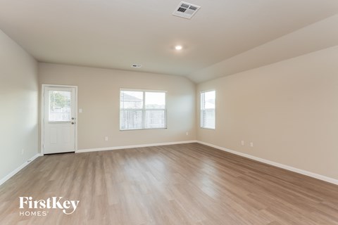 A spacious room with wooden flooring and a white door.