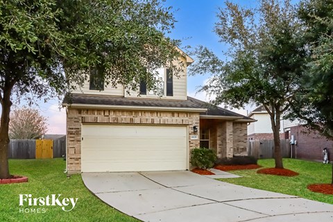 A house with a garage and a tree in front of it.
