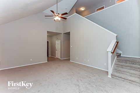 A spacious room with a staircase and a ceiling fan.
