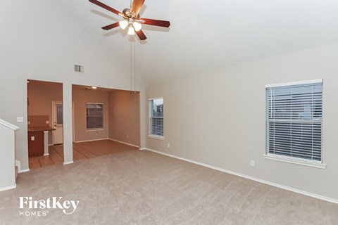 A spacious room with a ceiling fan and a window with blinds.