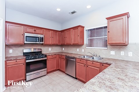A kitchen with red cabinets and stainless steel appliances.