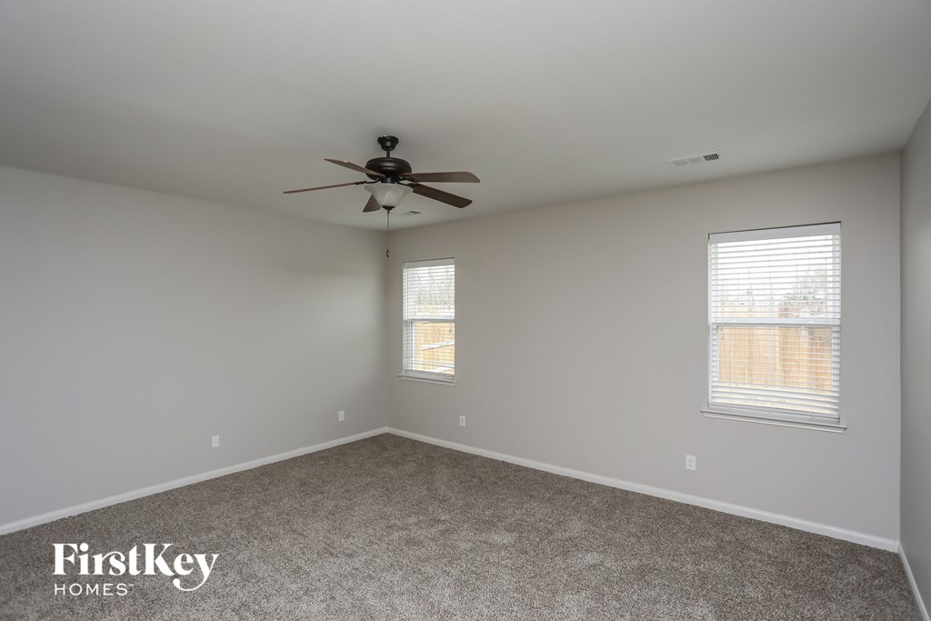 an empty room with a ceiling fan and two windows