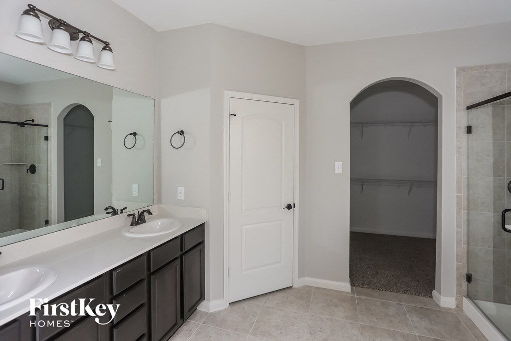 a master bathroom with two sinks and a large mirror and a walk in shower