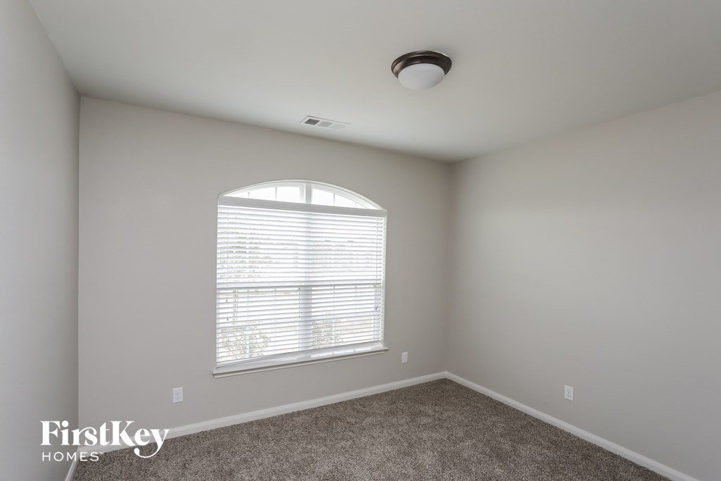 a bedroom with a large window and a carpet