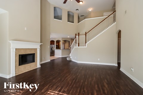 A spacious living room with wood flooring and a staircase leading to the upper level.