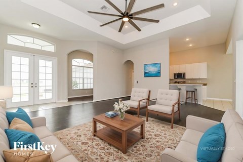 A living room with a ceiling fan and a painting on the wall.