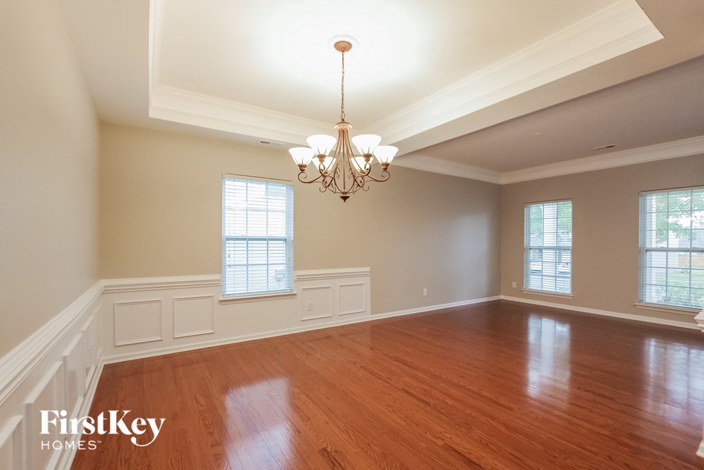 an empty dining room with wood floors and a chandelier