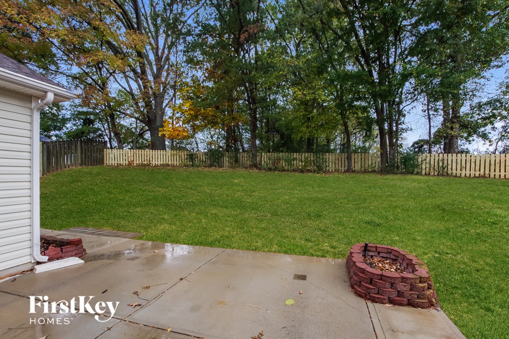 a backyard with green grass and a fence and a basket of grass