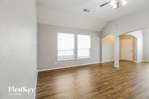 A spacious room with wooden floors and a ceiling fan.