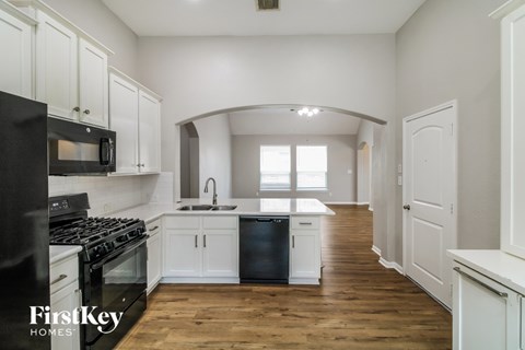 A kitchen with a black stove top oven and white cabinets.